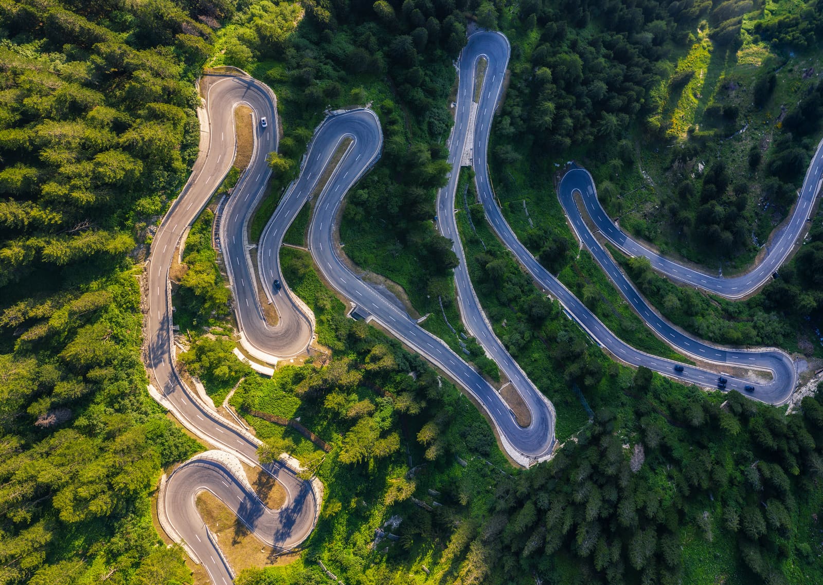The Maloja Pass seen from directly above, its hairpins folded back through forest.